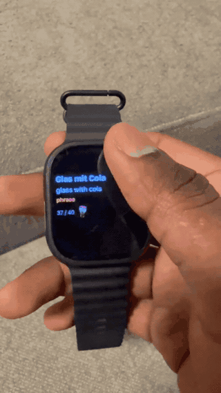 Vocabloot on a real Apple Watch Ultra: turning the Digital Crown through word cards like Glas mit Cola and der Kassenbon, with a sticker in between